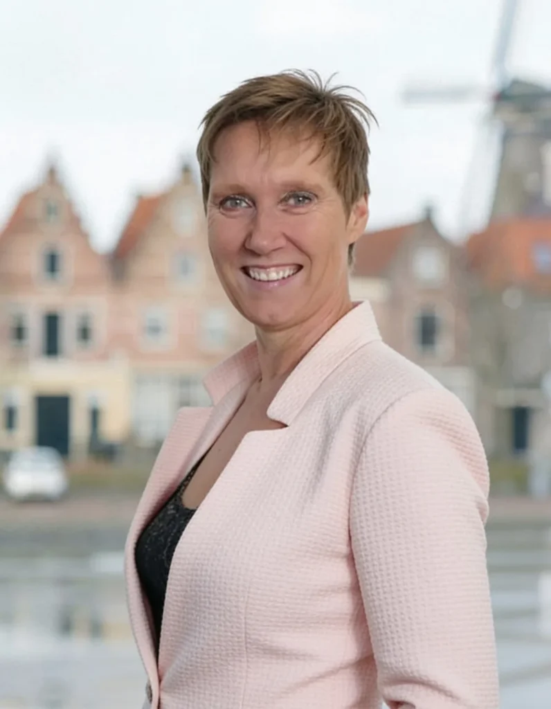 Een glimlachende vrouw in een roze jasje met een historische, Nederlandse achtergrond.