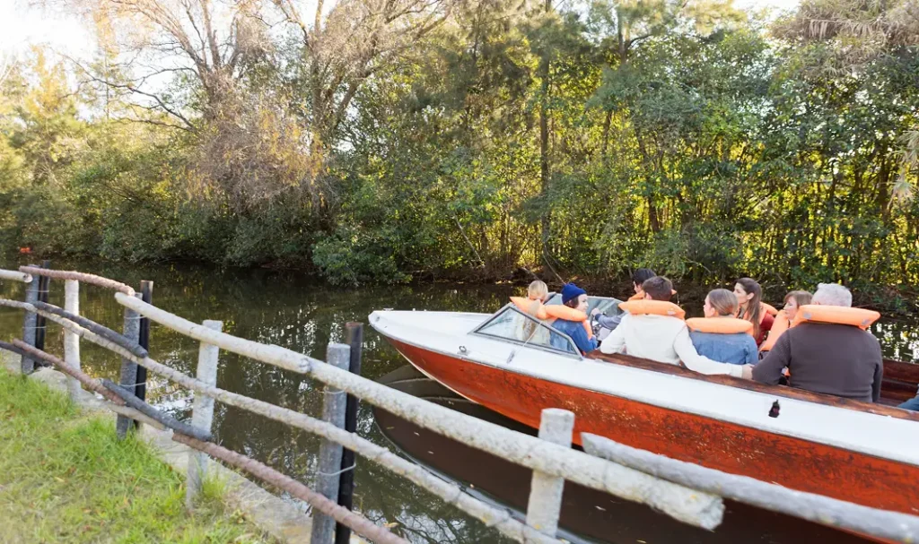 Gezelschap geniet van een boottocht op een smalle rivier omringd door bomen.